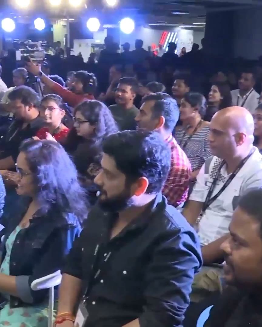 Rows of seated employees watching the stage, faces lit by the stage lighting