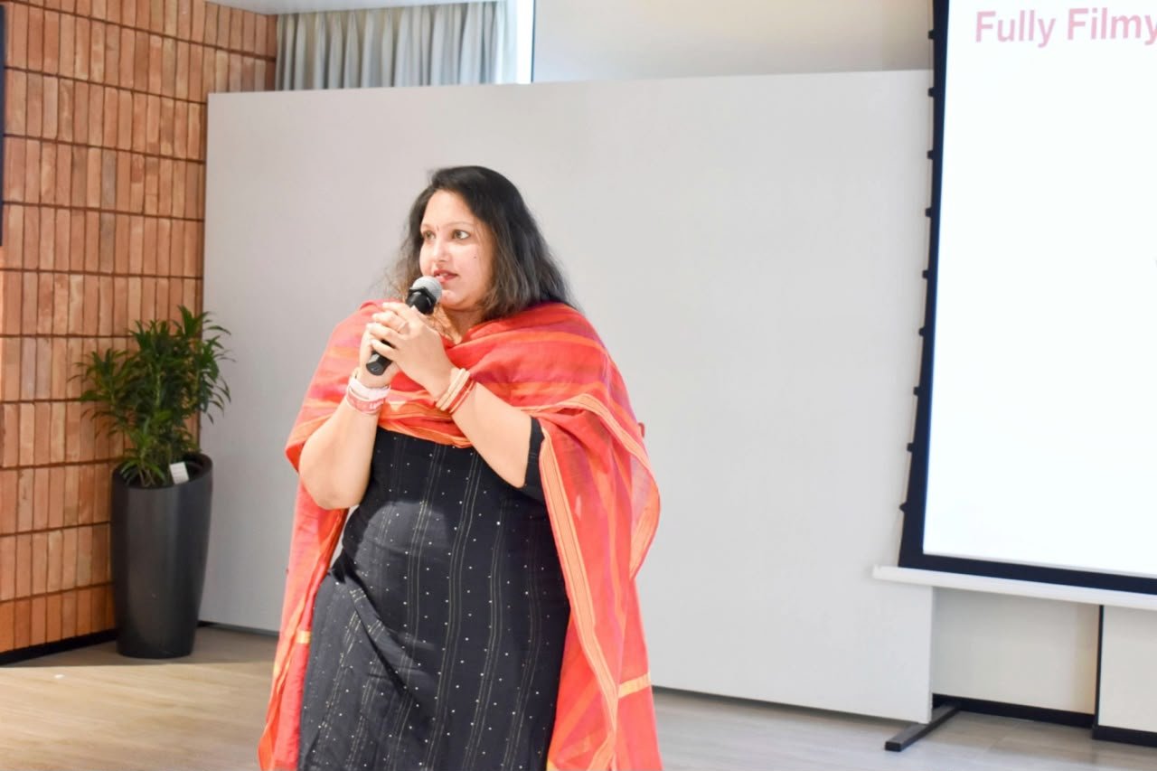 Pooja Aravalapalli hosting a corporate engagement session, presentation screen behind her